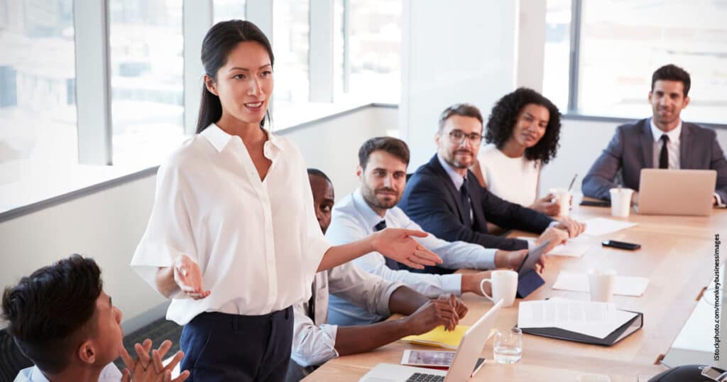 Asian businesswoman standing to address members in board meeting