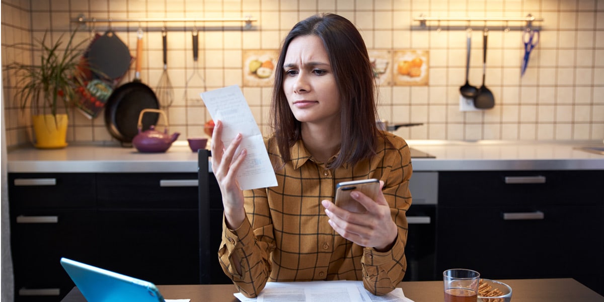 young woman expressing a perplexed look on her face while examining monthly bills and account balances