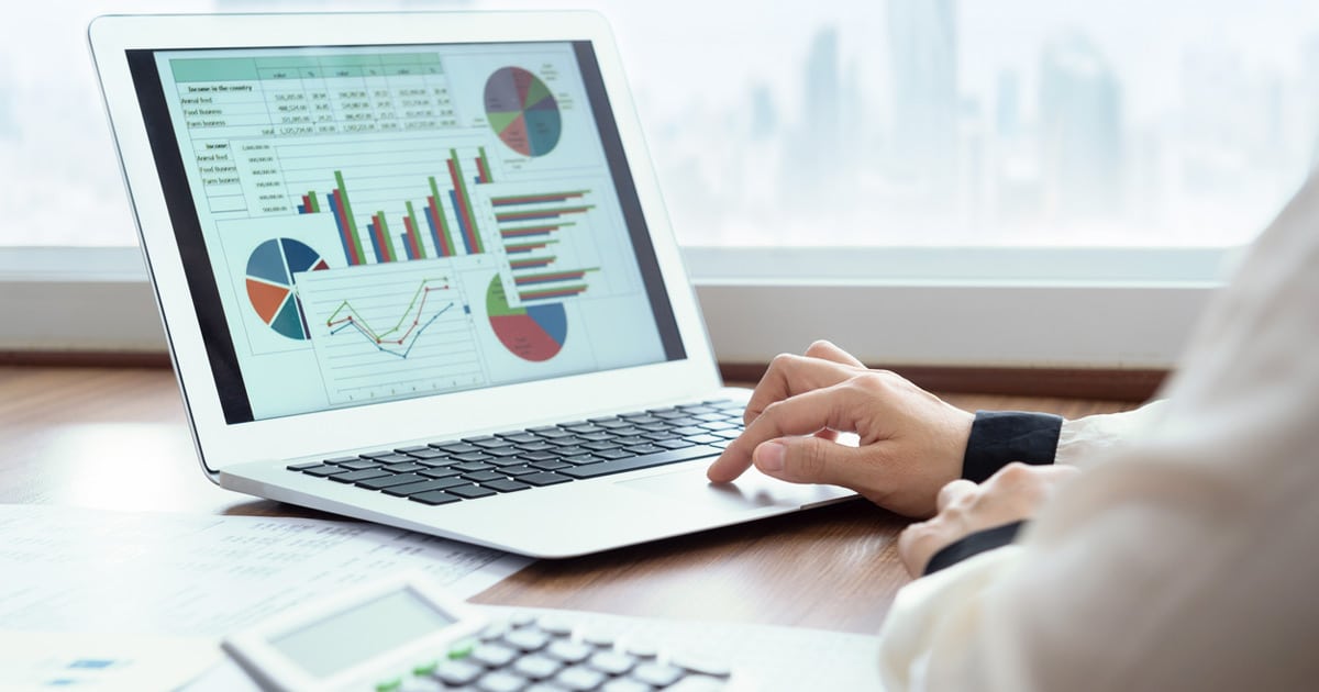 business woman reviewing income and expense report on computer while crunching numbers on a calculator