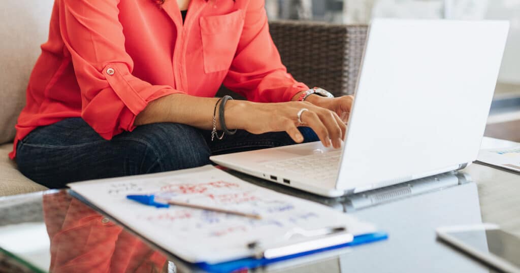 woman typing on laptop while sitting on couch