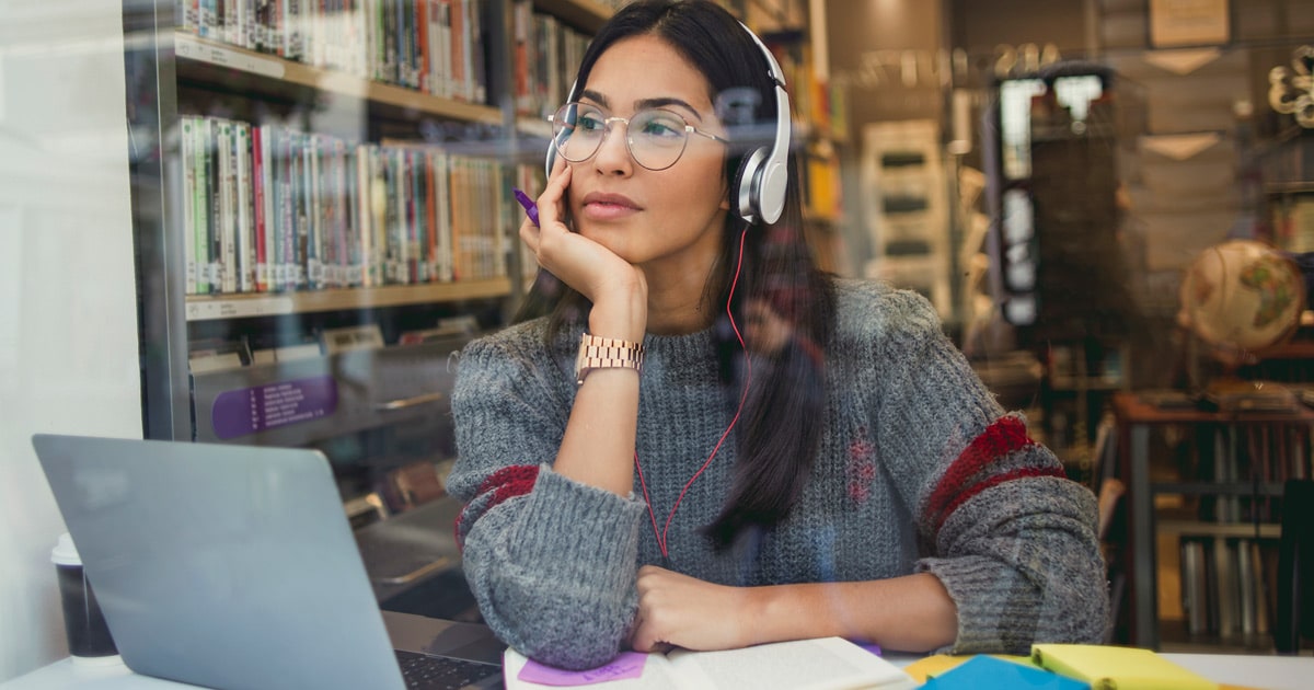 woman wearing headphones while working on her laptop in the library